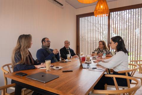 Un grupo de personas se reúne en una sala iluminada para compartir ideas y tomar café.