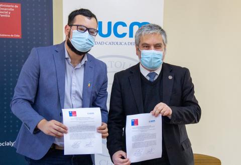 Dos hombres sonrientes sosteniendo documentos en un evento oficial.