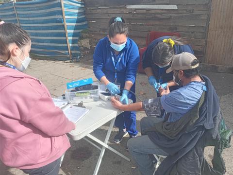 Un grupo de profesionales de la salud está realizando una atención médica comunitaria en un exterior.