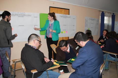 Un grupo de personas participa en una dinámica de trabajo en equipo en un salón de clases.