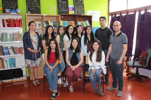 Un grupo de personas posando en una sala con estanterías llenas de libros.