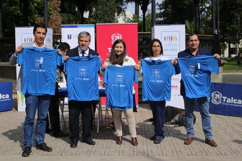 Un grupo de personas sostiene camisetas azules durante un evento al aire libre.