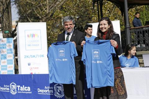 Dos personas sostienen camisetas azules en un evento relacionado con deportes en Talca.