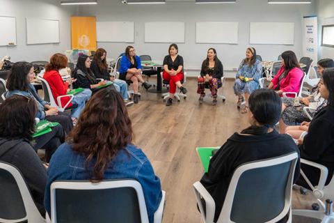 Un grupo de mujeres sentadas en círculo durante una reunión o taller.