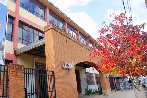 Edificio de la UCM rodeado de árboles con hojas de otoño.