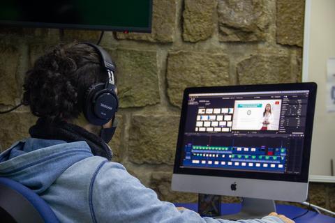 Una persona está editando un video en una computadora mientras usa auriculares.