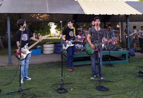 Un grupo de jóvenes toca en un concierto al aire libre en un parque.