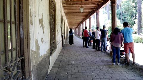 Una fila de personas en un pasillo con paredes descascaradas.