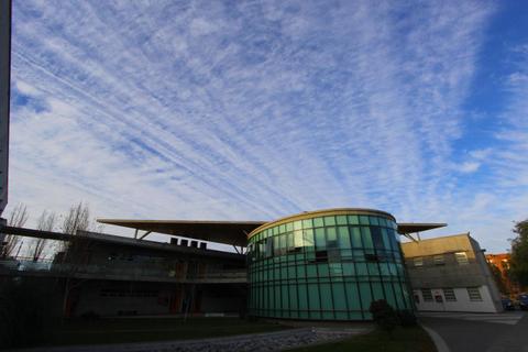 Una moderna edificación de vidrio con un cielo nublado al fondo.