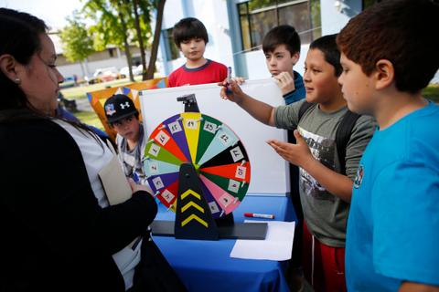 Un grupo de niños observa una ruleta de juego mientras interactúan entre ellos.