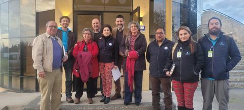 Grupo de personas posando frente a un edificio con grandes ventanales.