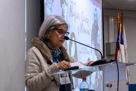 Una mujer de cabello gris con gafas está hablando en un evento sobre mujeres, memoria y derechos humanos.