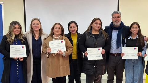 Un grupo de personas sonríe mientras sostiene certificados en un evento.