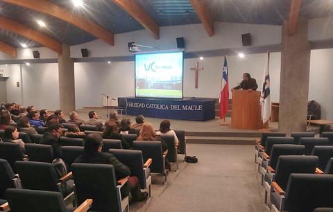 Una conferencia en la Universidad Católica del Maule con un orador frente a una audiencia.