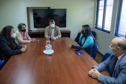 Un grupo de cinco personas con mascarillas se sienta alrededor de una mesa en una sala de reuniones.