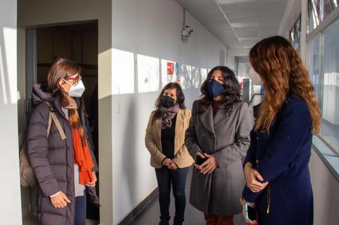 Un grupo de mujeres conversando en un pasillo con mascarillas durante la pandemia.