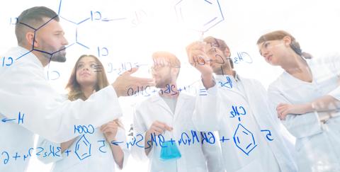 Un grupo de científicos chilenos discutiendo ideas frente a una pizarra llena de fórmulas químicas.