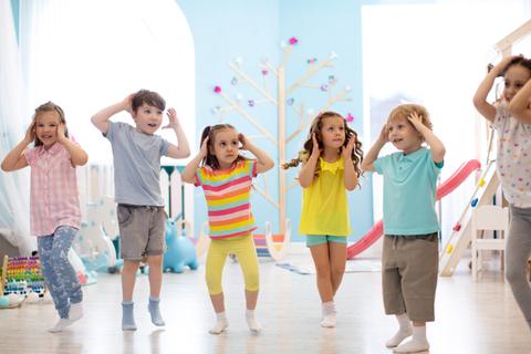 Un grupo de niños bailando y divirtiéndose en un salón luminoso.