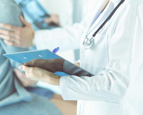 Un médico revisa un informe mientras atiende a un paciente en un consultorio.