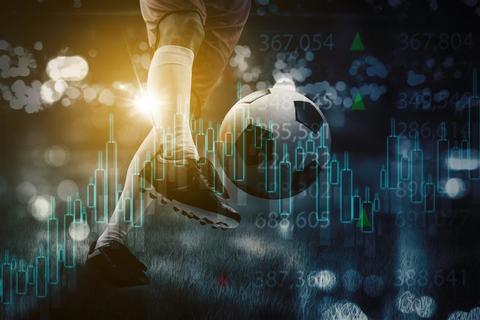 Un jugador de fútbol está pateando un balón en medio de gráficos financieros digitales.
