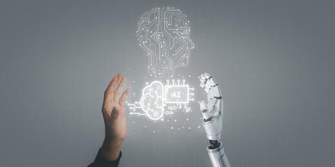 Un humano y un robot se están conectando a través de sus manos, simbolizando la interacción entre la tecnología y la humanidad.