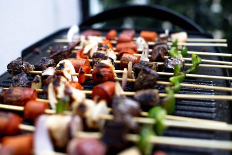 Un asado con una variedad de brochetas llenas de carne y verduras.