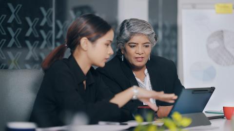 Dos mujeres conversando sobre un proyecto mientras revisan una tablet.