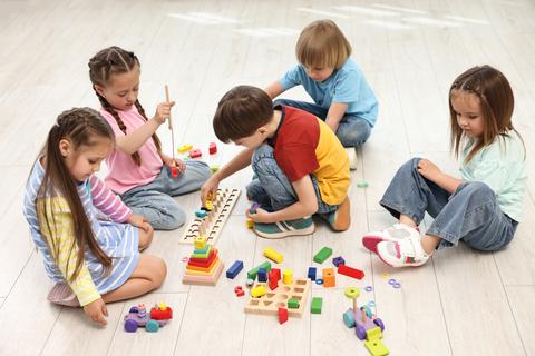 Un grupo de niños jugando y aprendiendo con bloques de colores en el suelo.