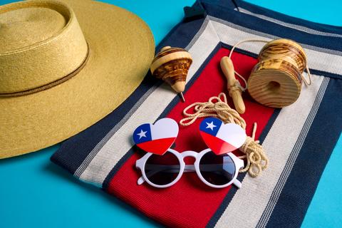 Un conjunto de elementos tradicionales chilenos, incluyendo un sombrero, juguetes y lentes con los colores de la bandera.