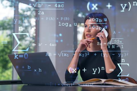 Una mujer está hablando por teléfono mientras trabaja en su computador con fórmulas matemáticas de fondo.
