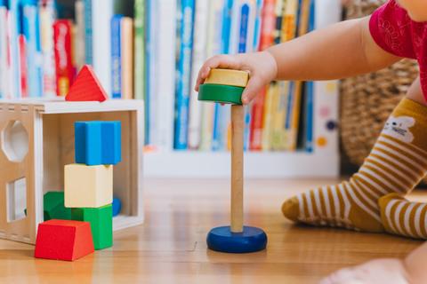 Un niñito está jugando con bloques de colores en el suelo de una sala.