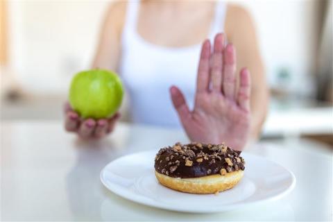 Una persona elige una manzana verde en vez de un donut.
