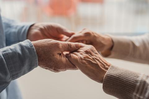 Un par de manos entrelazadas que simbolizan amor y conexión entre dos personas mayores.