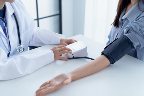 Un médico está tomando la presión arterial de una paciente en un consultorio.