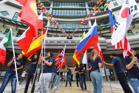 Un grupo de personas sostiene banderas de diferentes países frente a un edificio.