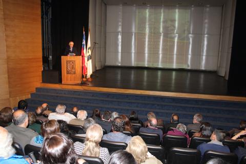Una conferencia en un auditorio con un orador frente a una audiencia numerosa.