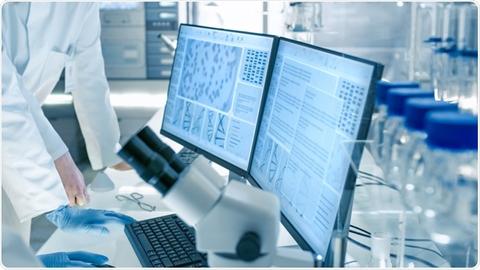 El laboratorio presenta un investigador trabajando con microscopios y pantallas de datos.