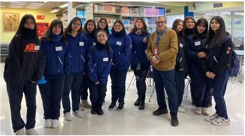 Un grupo de estudiantes y un profesor posan juntos en una biblioteca.