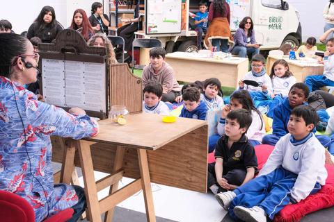 Un grupo de niños escucha atentamente a una narradora en un ambiente educativo.