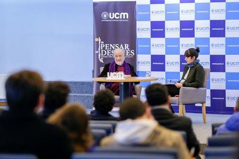 Una charla en la Universidad Católica de Murcia con un ponente y una moderadora frente a un público atento.