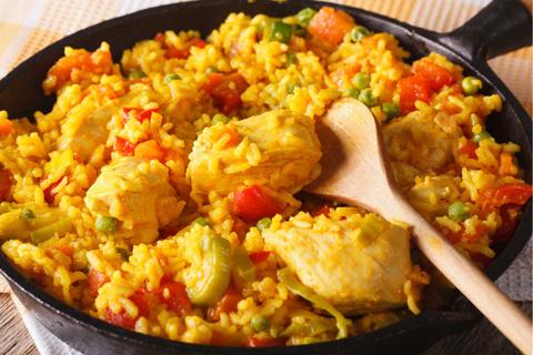 Un plato de arroz con pollo y verduras en una sartén.