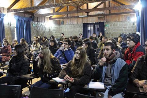 Un grupo de personas sentadas en un aula prestando atención durante una presentación.