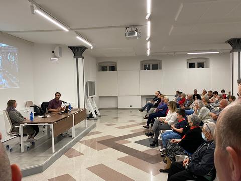 Una conferencia en un salón con muchas personas escuchando atentamente a los ponentes.