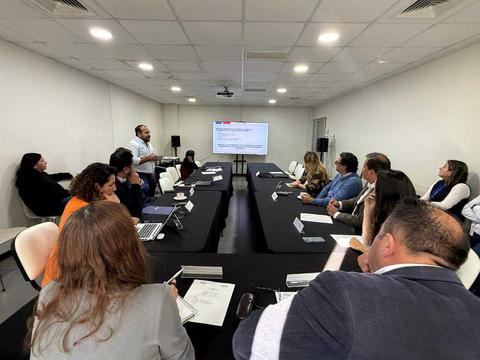 Una reunión en una sala con participantes atentos a una presentación en pantalla.