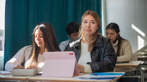 Un grupo de estudiantes en un aula, con una tablet en la mesa y un ambiente de estudio.