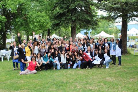 Un gran grupo de personas posando alegremente al aire libre en un día soleado.