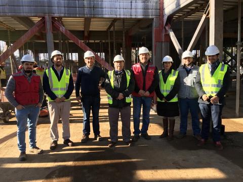 Grupo de personas vistiendo chalecos y cascos de seguridad en un sitio de construcción.