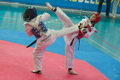 Dos competidoras de taekwondo luchando en un torneo.