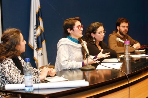 Un grupo de personas discutiendo en una mesa durante un evento académico.