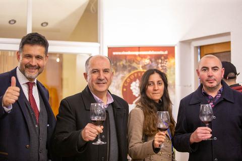 Un grupo de cuatro personas sonrientes sostiene copas de vino en un evento social.